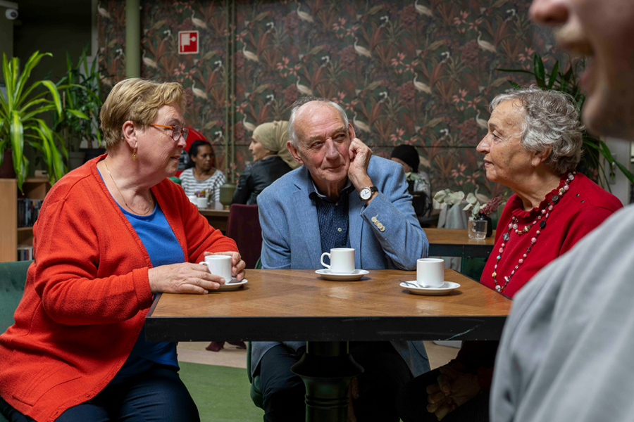 Drie mensen aan een tafel met kopjes koffie